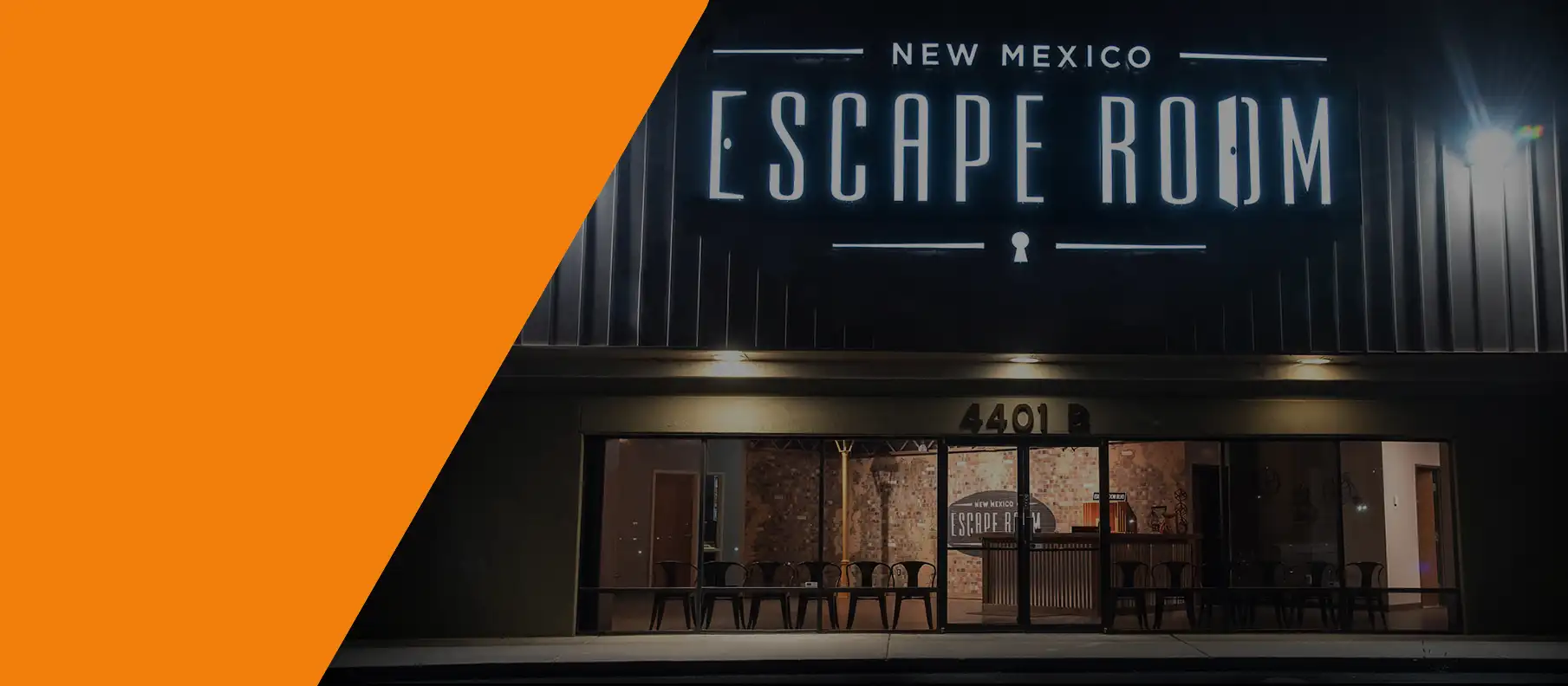 Night view of the New Mexico Escape Room storefront with a large glowing brand sign above glass entry doors